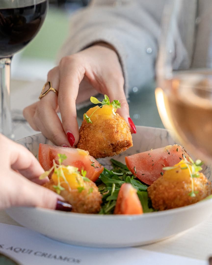 Petisco da casa com salada e copo de vinho